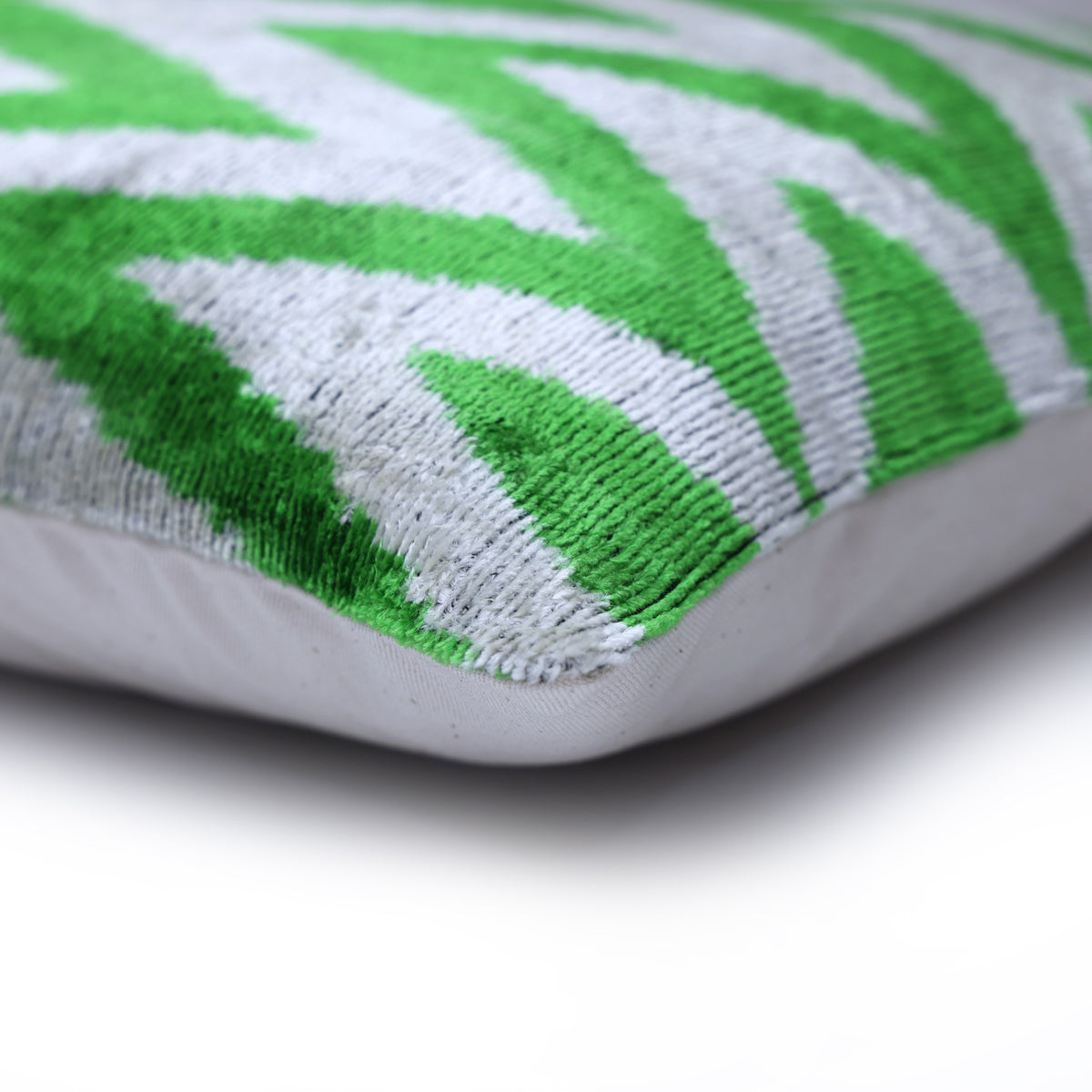 Corner and edge detail of bright green and light gray velvet lumbar pillow
