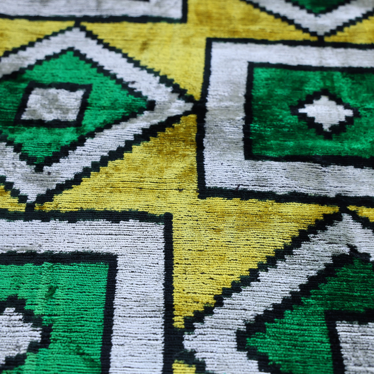 Close view of geometric silk velvet with saffron yellow, emerald teal, ivory and inky black shapes