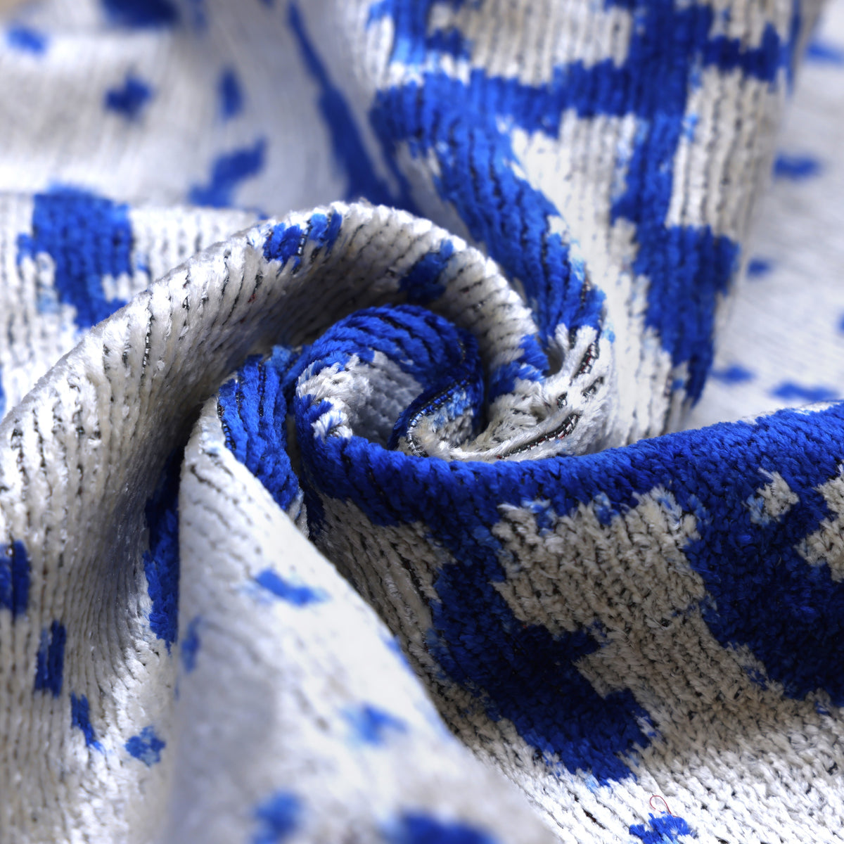 Tight view of the botanical swirls across cobalt blue and silver gray velvet