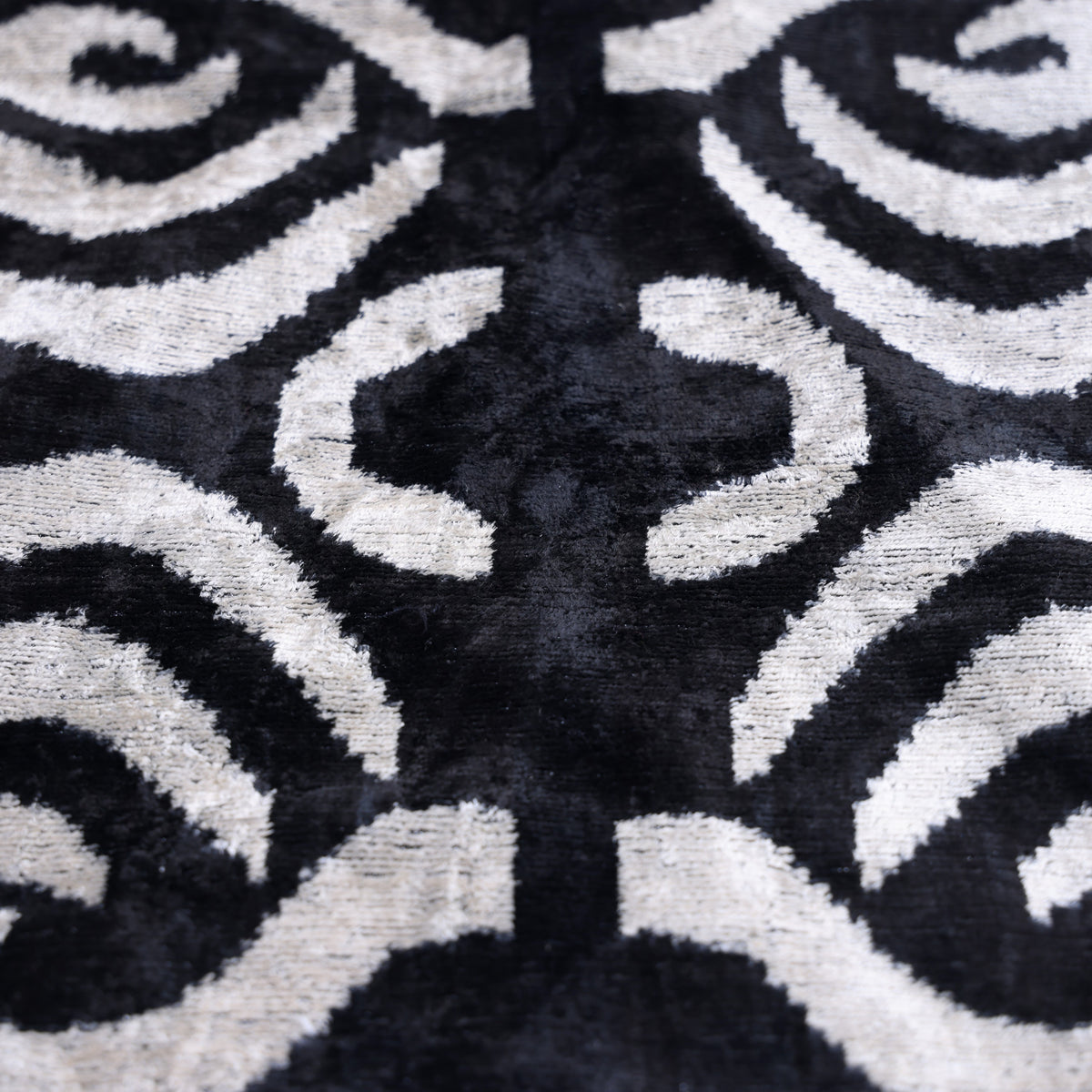 Close-up of inky black and soft ivory silk velvet in an abstract ikat pattern