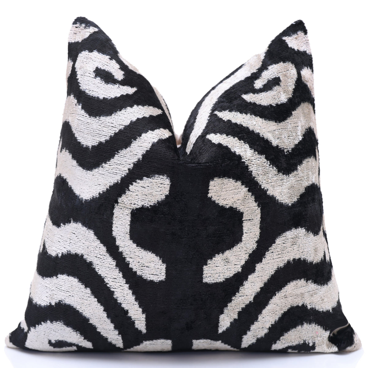 Angled view of the black and ivory ikat pillow styled with a center karate chop