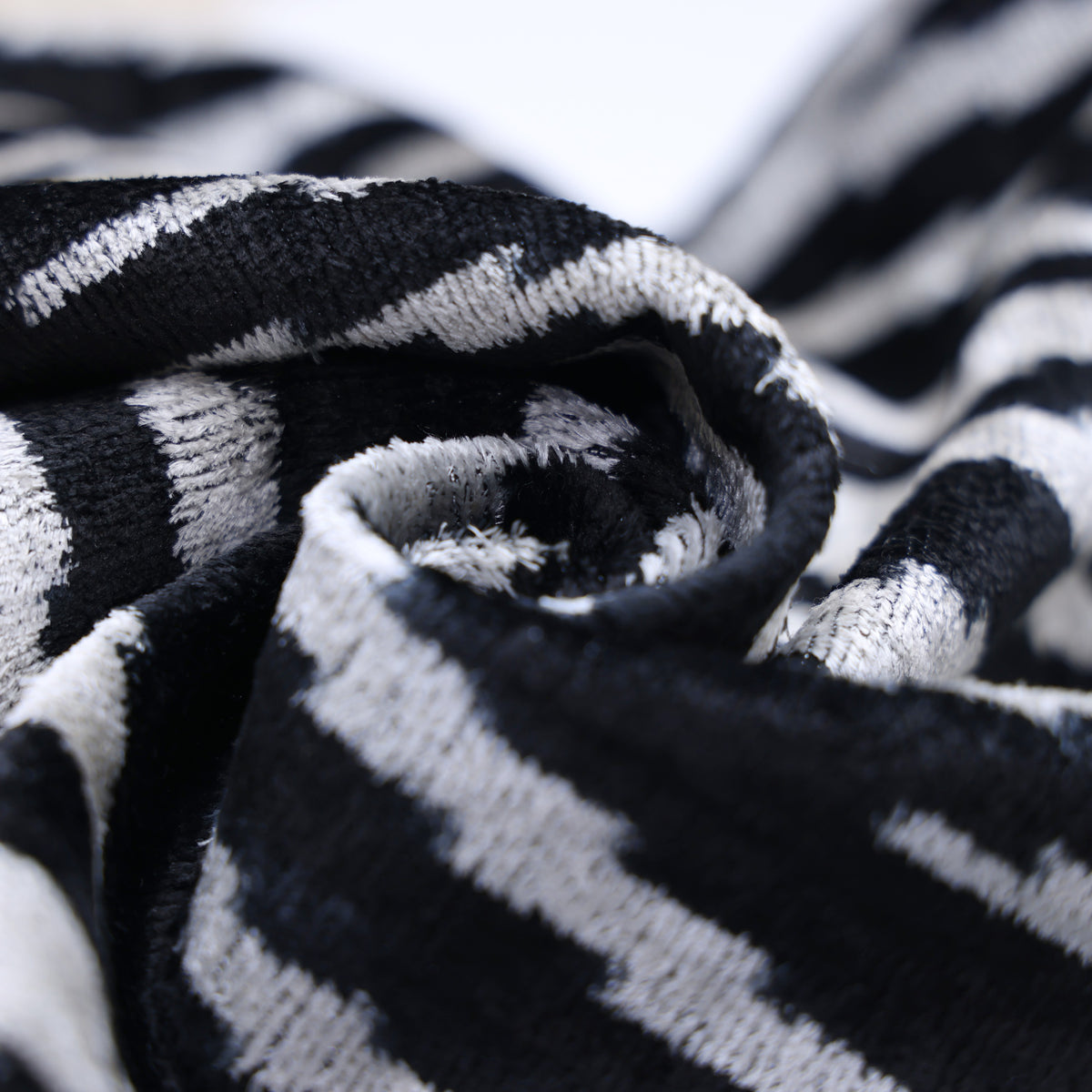 Swirled inky black and soft ivory velvet textile showing the fabric's soft sheen and texture