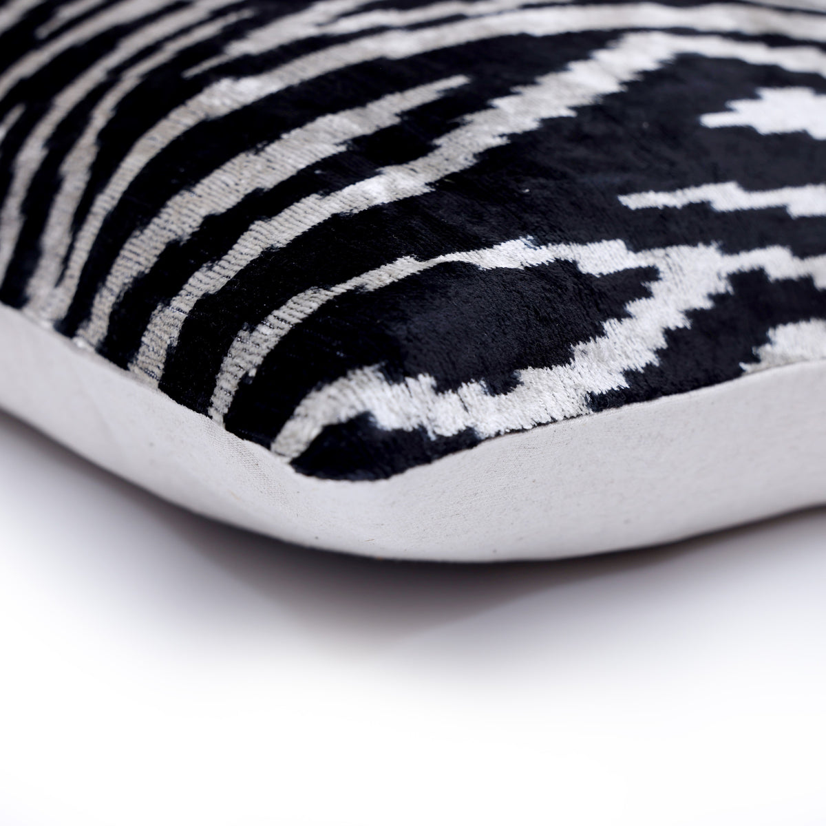 Corner detail of inky black and soft ivory velvet front with solid linen reverse