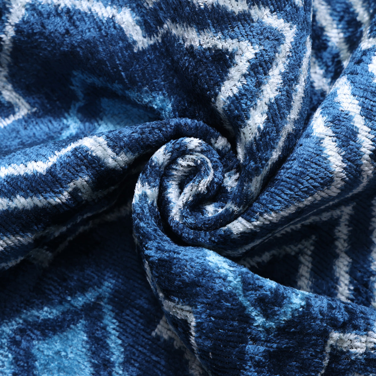 Close view of medium denim blue velvet pile with white and navy geometric pattern