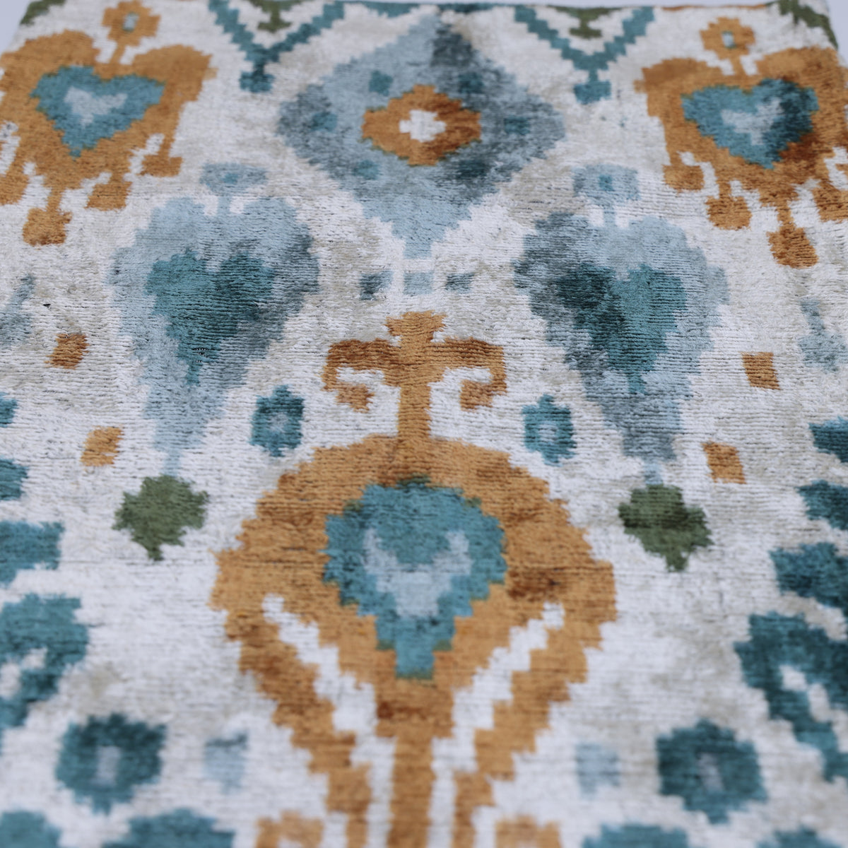 Overhead detail of the central ikat medallion in teal, ochre gold and sky blue