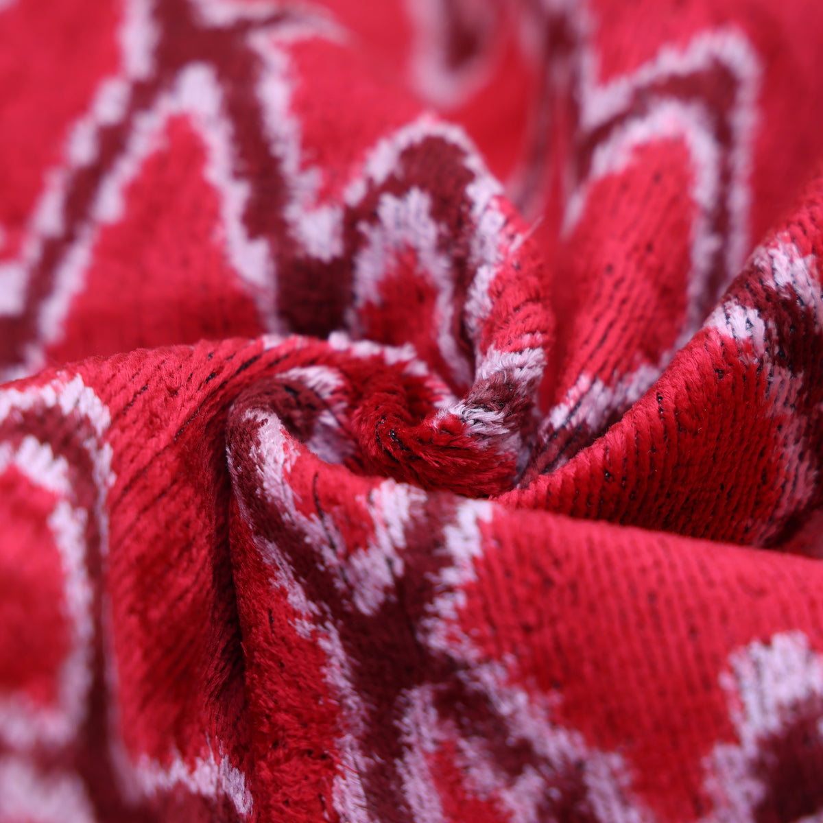 Close-up of gathered cherry red velvet folds with visible textured pile