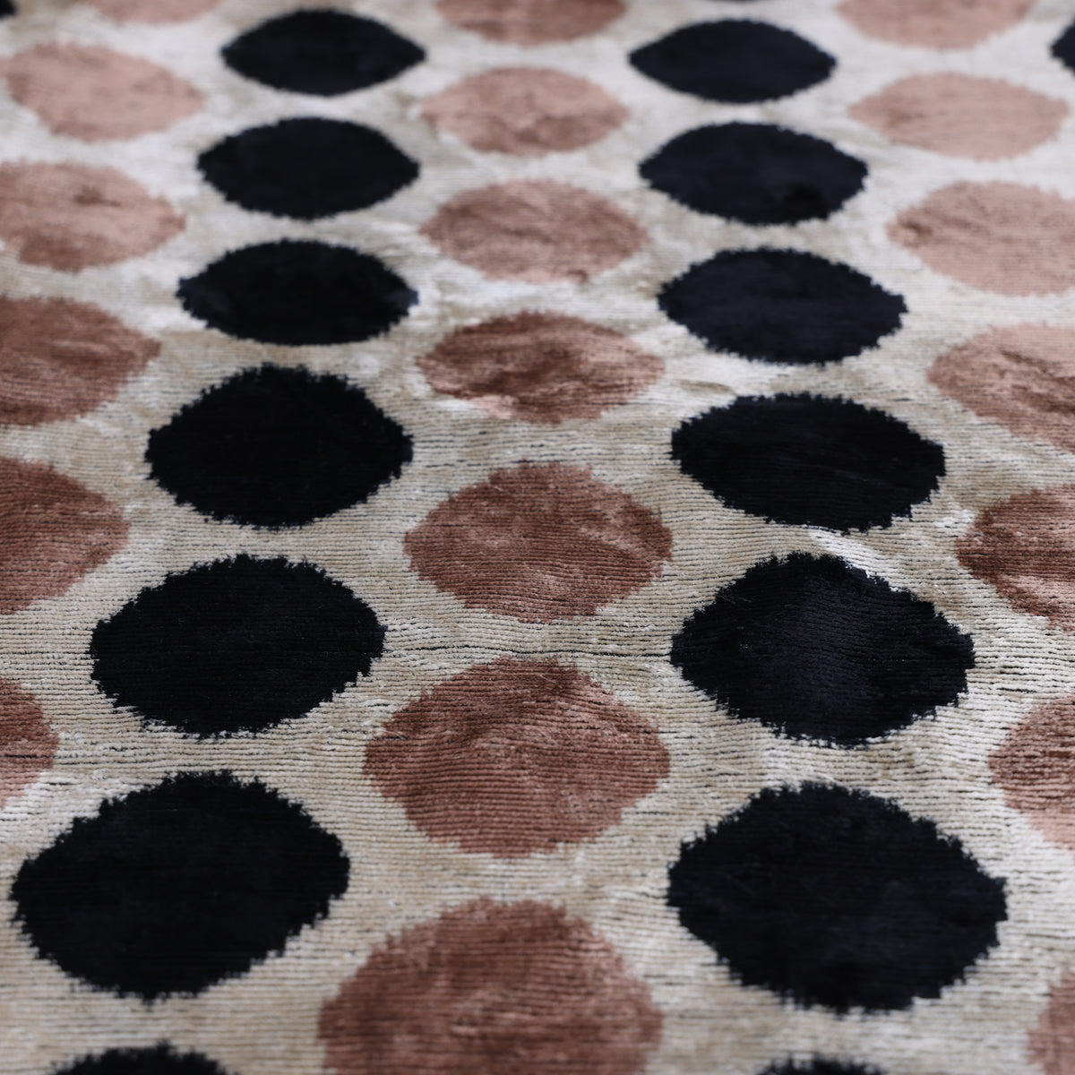 Angled view of dusty blush rose and black ikat-edged dots with velvet sheen