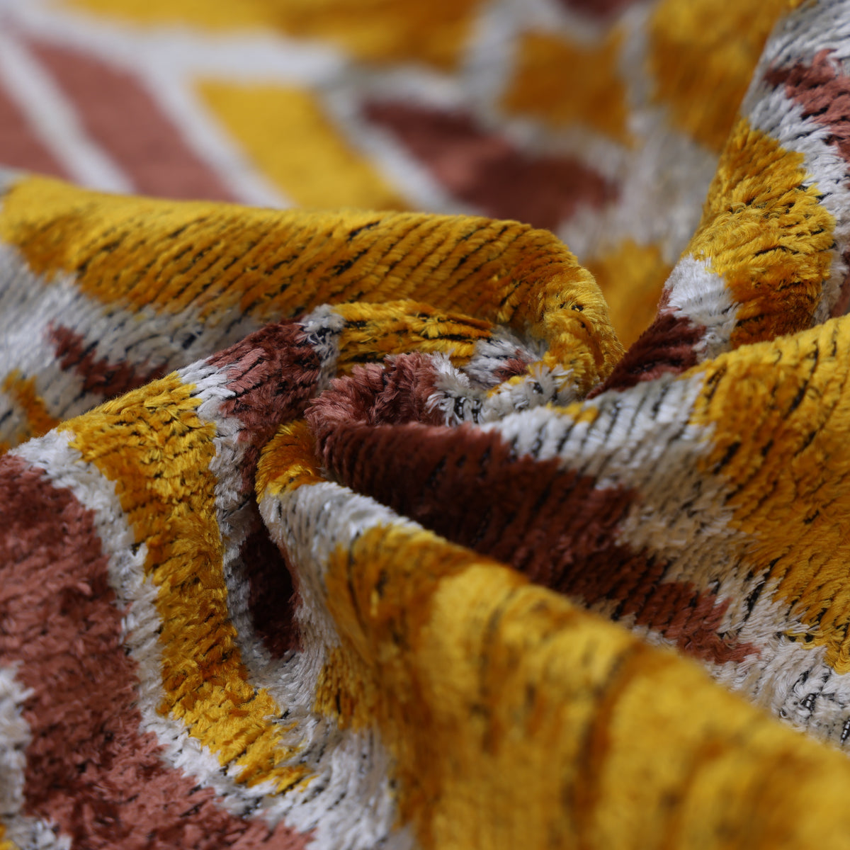 Low-angle view of swirled mustard gold velvet pile and dusty rose lattice