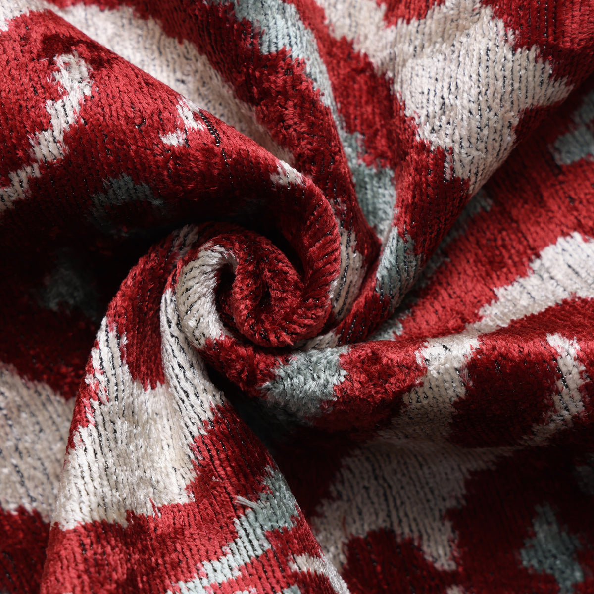 Close view of crimson red and warm ivory velvet pile with pale sage aqua accents