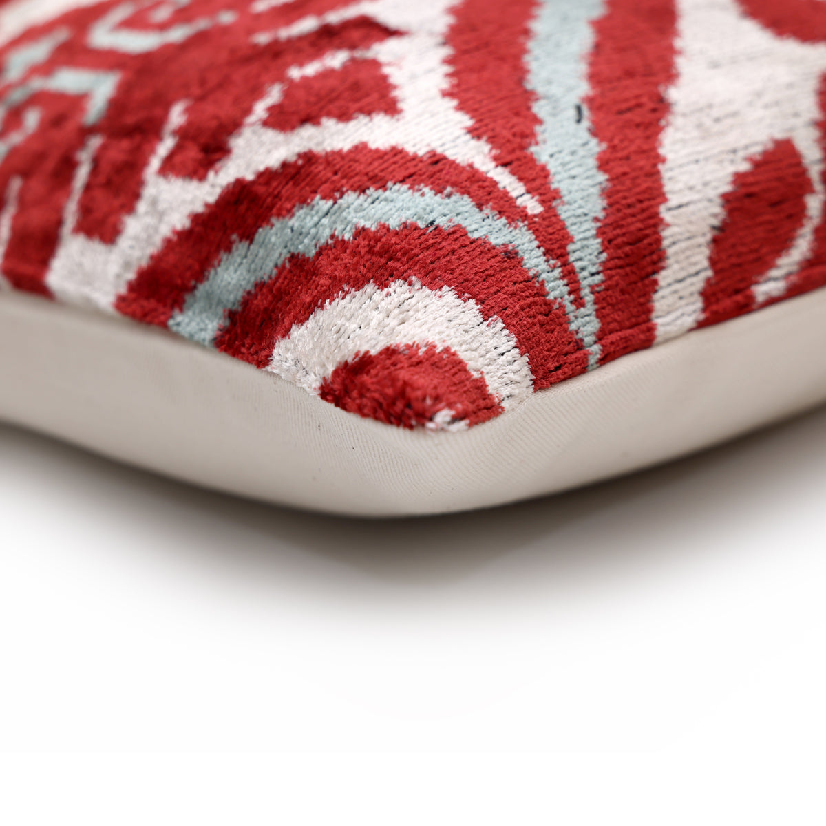 Corner detail of the crimson red and warm ivory pillow's piping-free seam