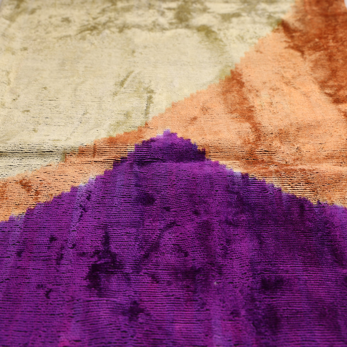 Overhead detail of diagonal transitions between purple, gold and terracotta orange velvet