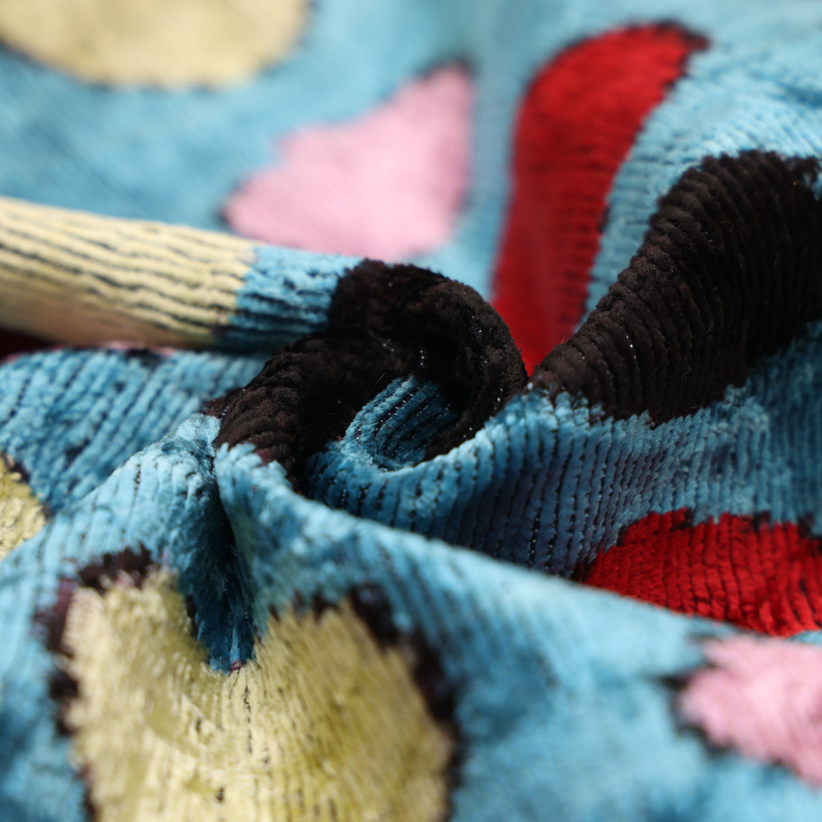 Macro view of the ribbed velvet pile in cerulean blue with multicolor polka dots
