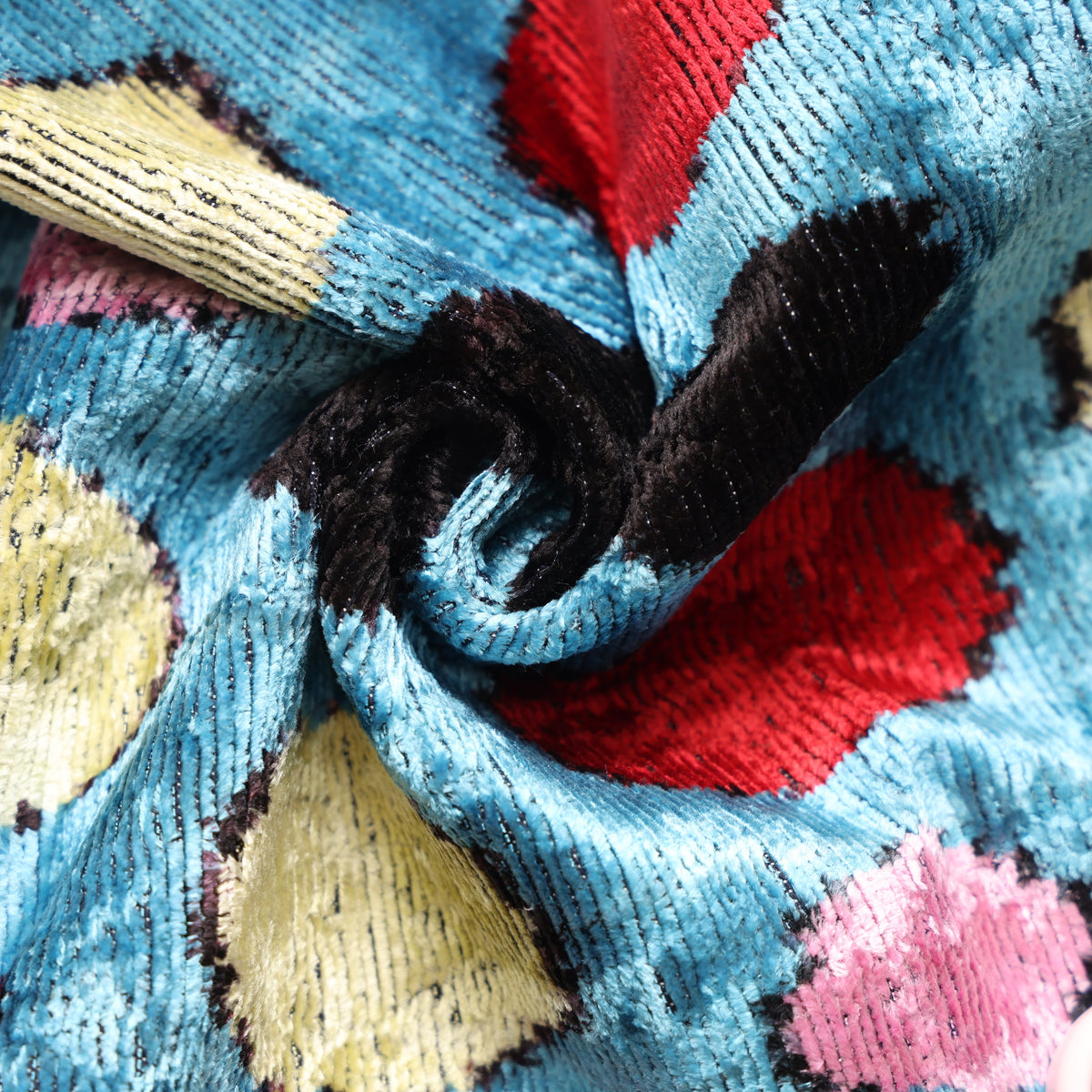 Close-up of cerulean blue ribbed silk velvet with black, crimson red, pale yellow and light pink spots