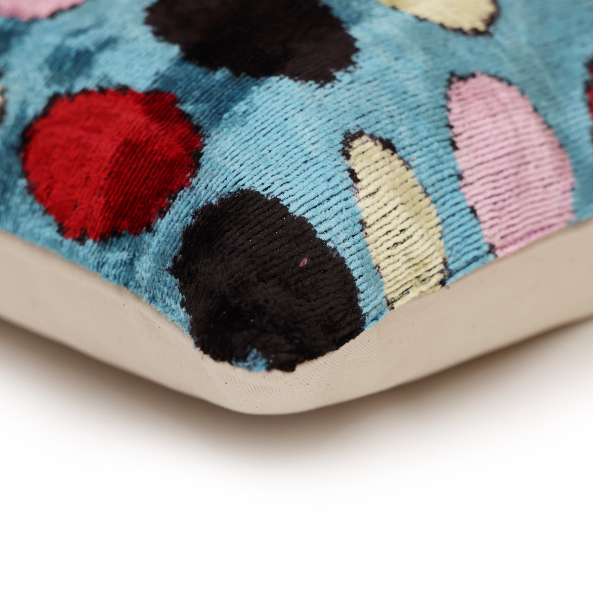 Corner detail of cerulean blue polka dot velvet, seam and light neutral backing
