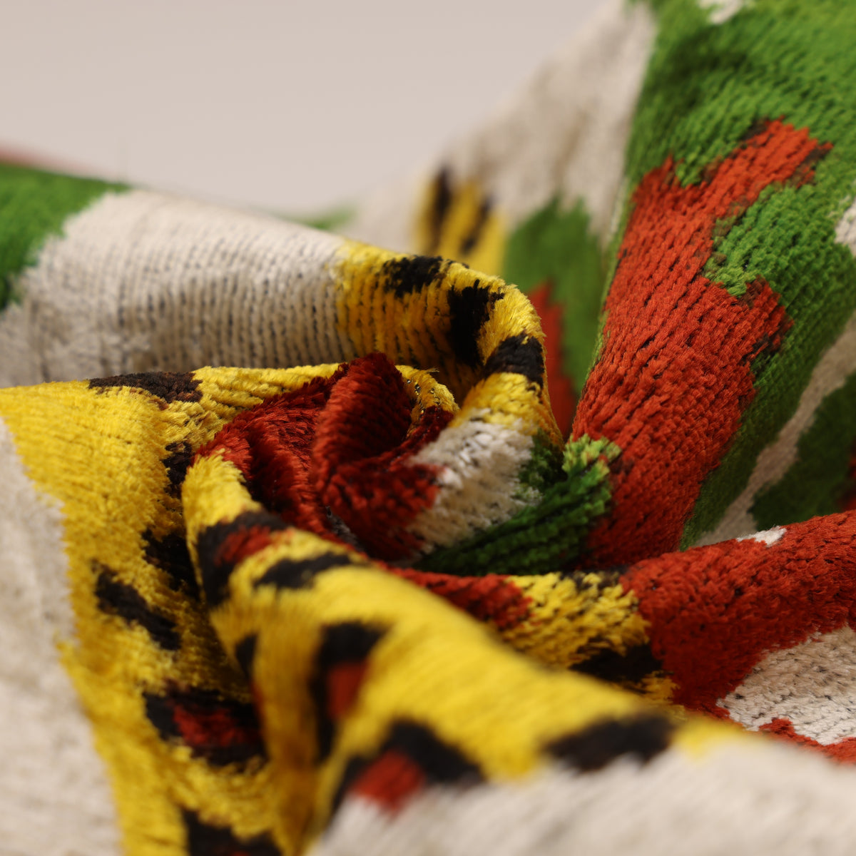 Close-up of plush silk velvet showing light oatmeal beige, rust, yellow and green texture