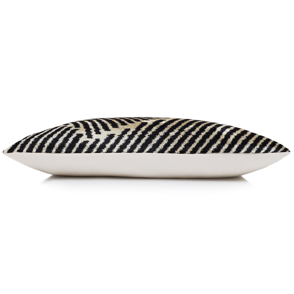 Side profile of the jet black and champagne beige lumbar pillow with light backing