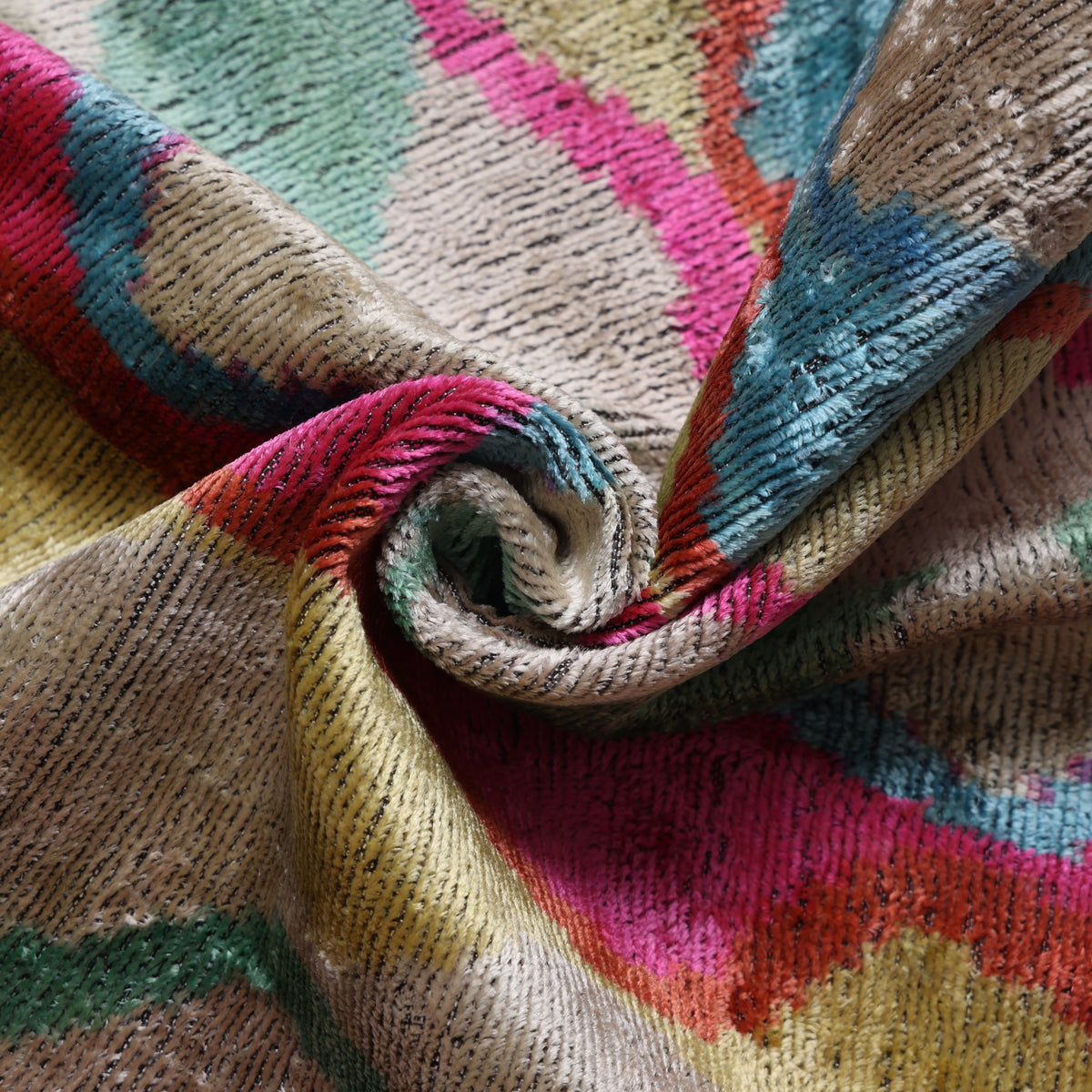 Folded silk velvet showing champagne beige, magenta pink and antique gold wavy ikat texture