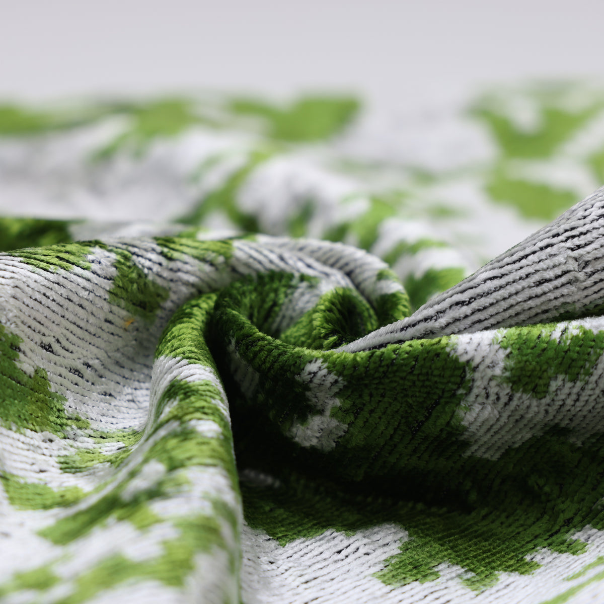 Gathered folds highlight the cut-pile texture of the leaf green ikat velvet