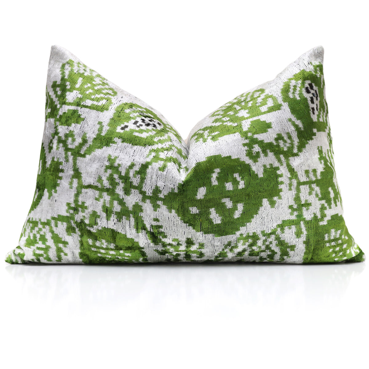 Silvery white and leaf green pomegranate ikat pillow styled on a reflective surface
