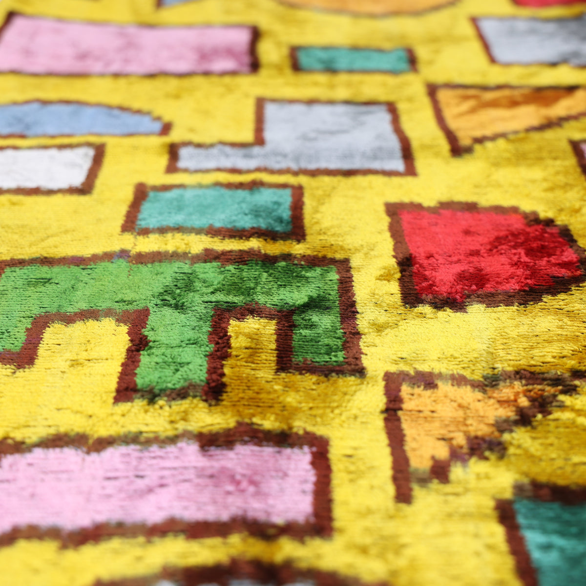 Angled bright mustard yellow velvet surface showing geometric motifs and changing pile