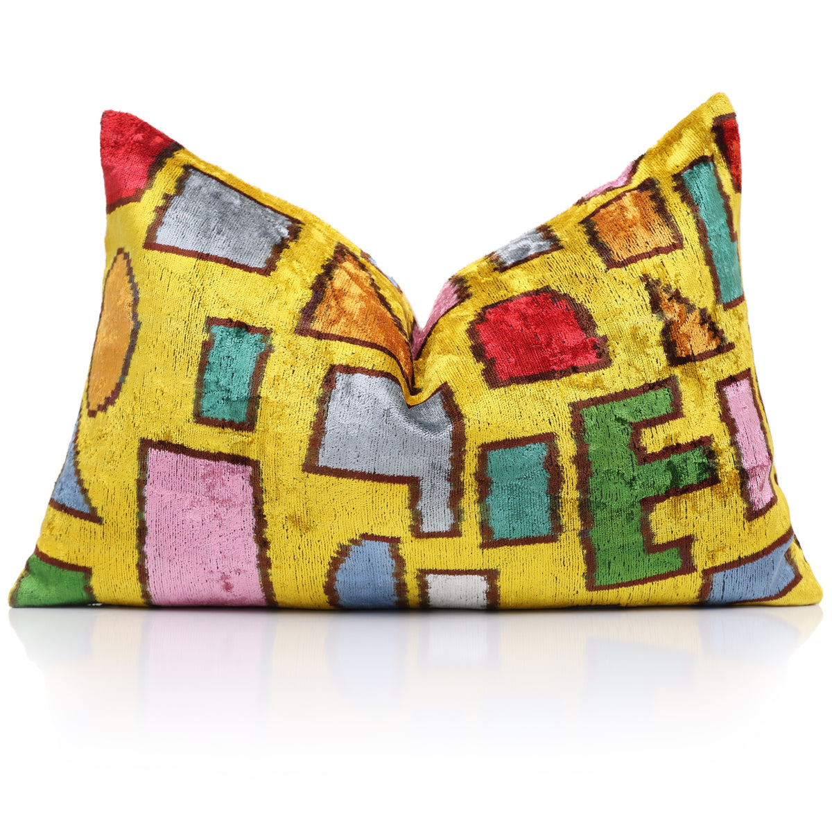 Styled mustard and multicolor geometric lumbar pillow with a shaped center on reflective surface