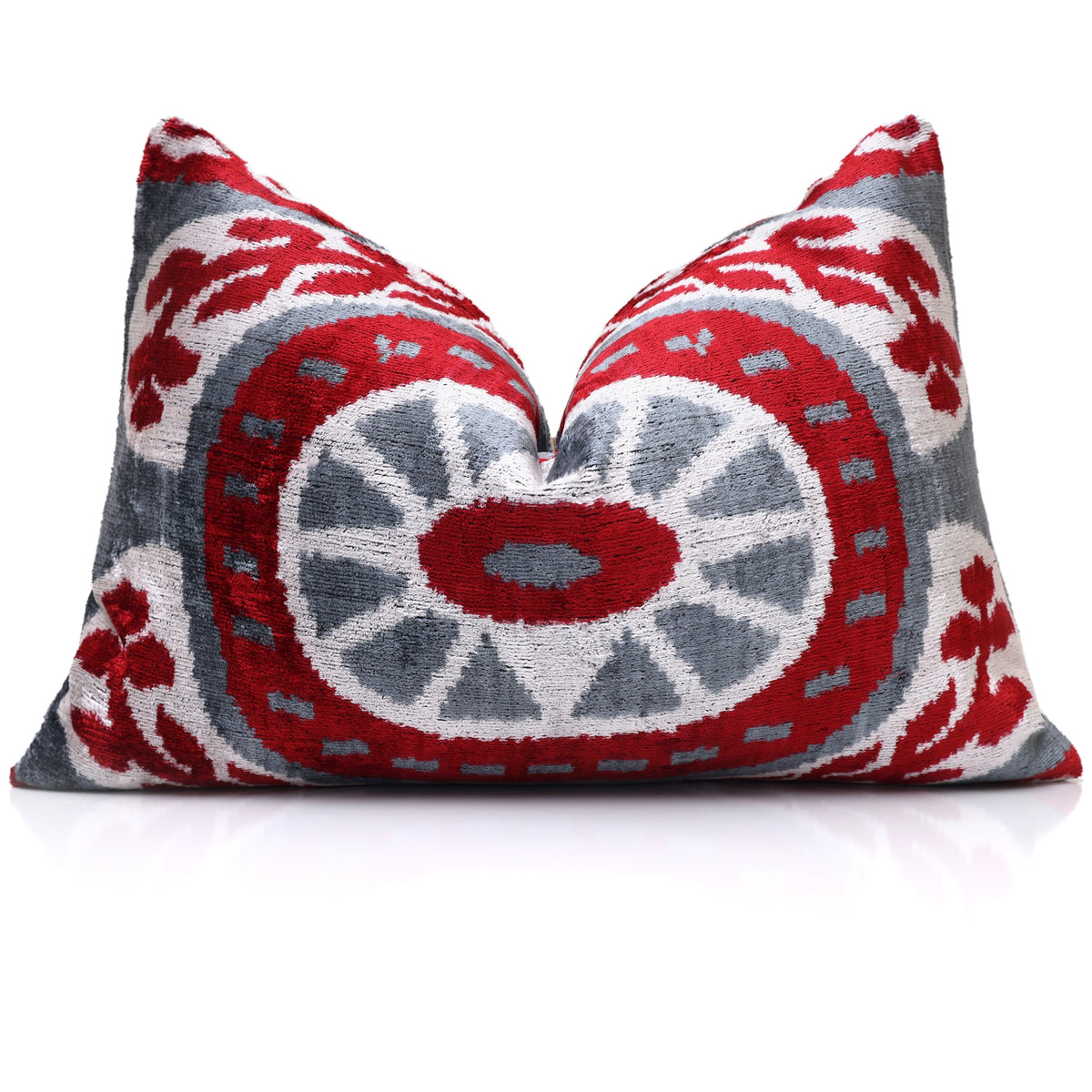Crimson red and slate gray ikat lumbar pillow standing upright on a reflective surface