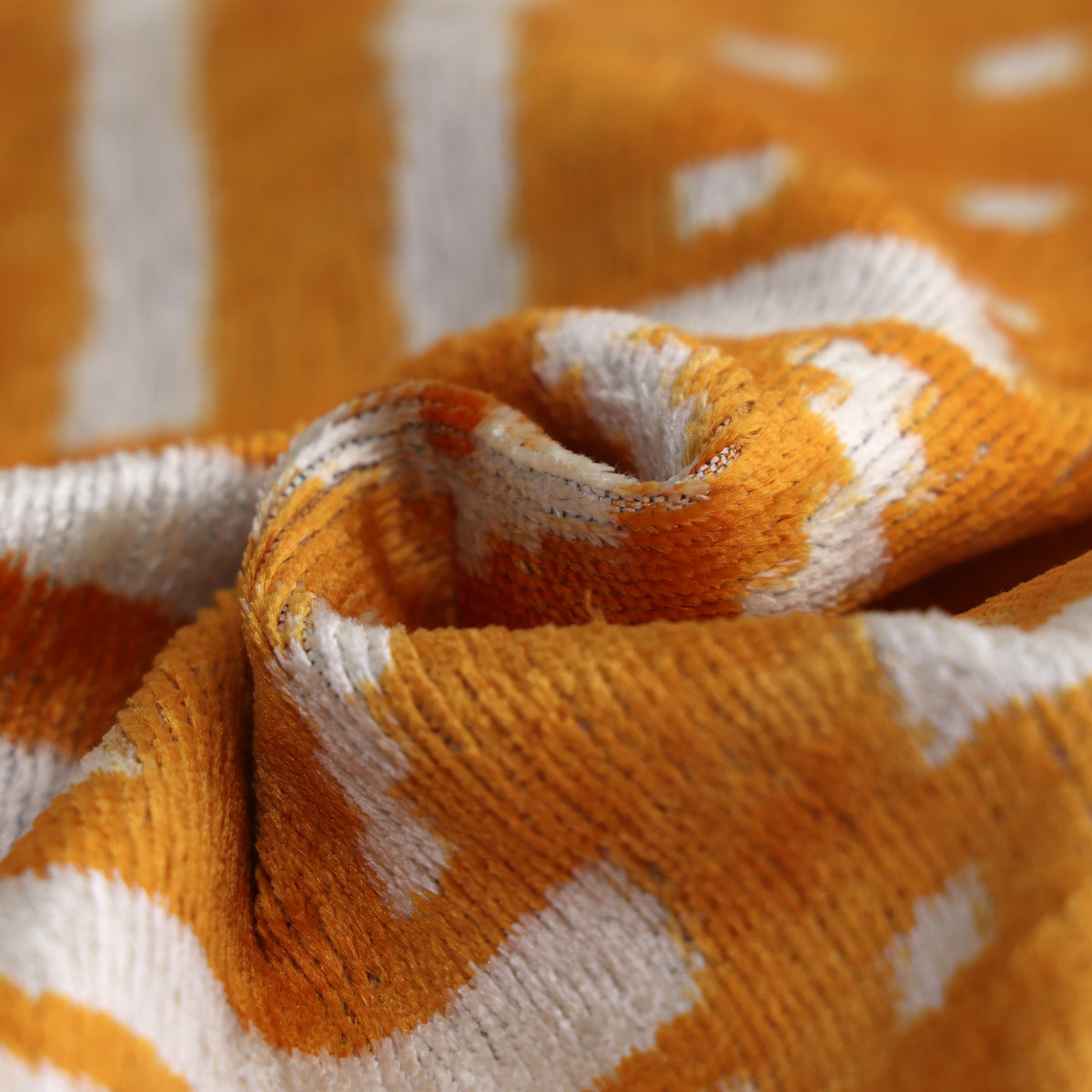 Swirl detail highlighting sheen across marigold yellow and ivory white geometric velvet