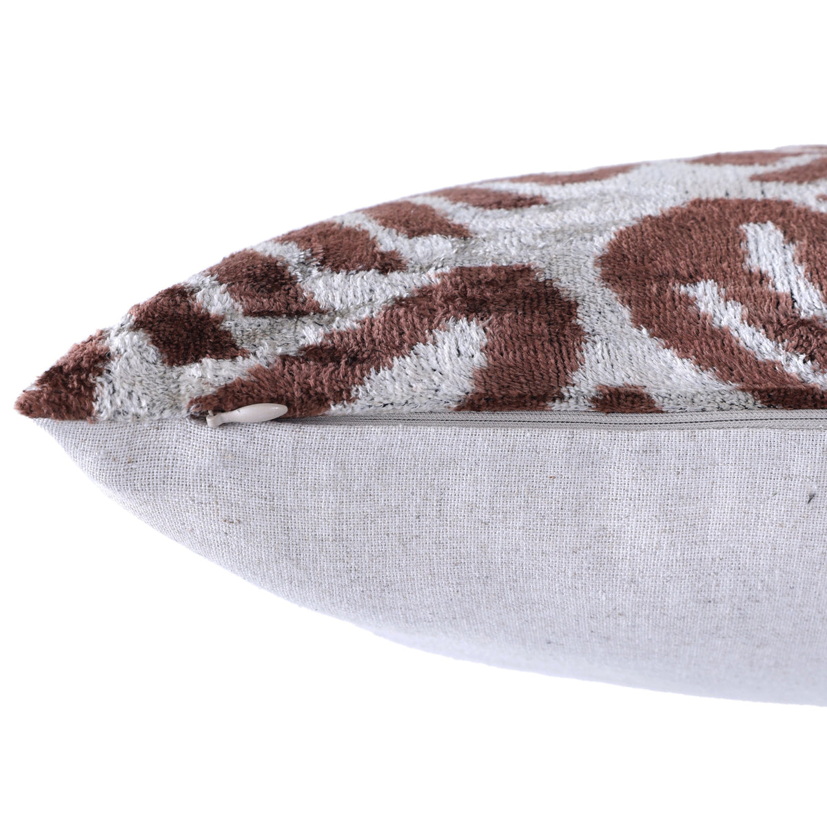 Close-up of hidden zipper along the bottom edge of a warm brown and silvery white pillow