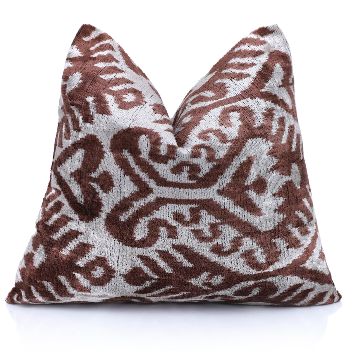 Styled front view of warm brown and silvery white ikat velvet pillow with center karate chop