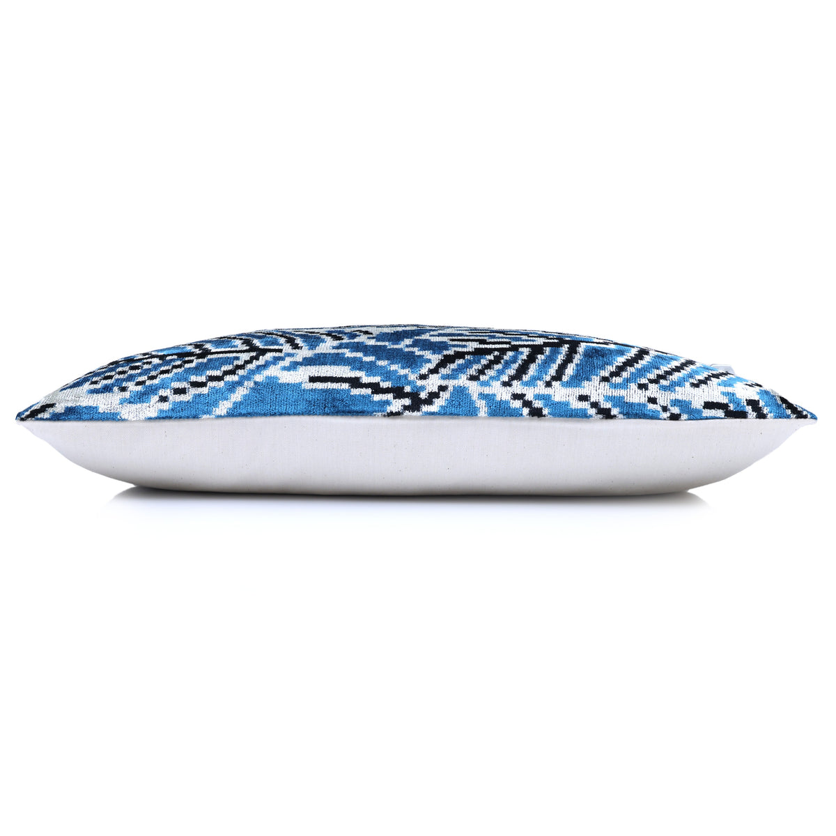 Side profile of a blue and white lumbar pillow showing its depth and backing