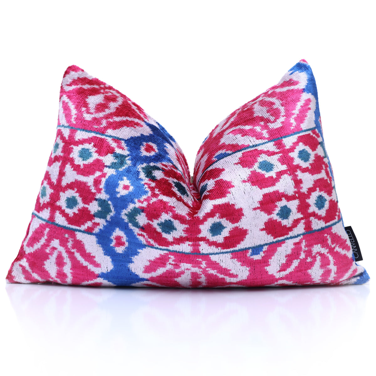 Upright magenta pink and white ikat lumbar pillow on a reflective surface
