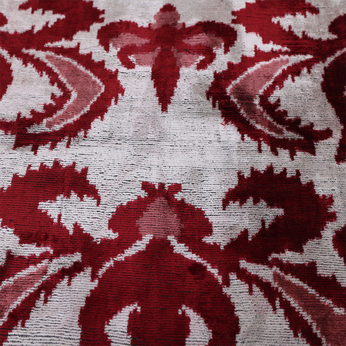 Central ikat floral medallion in deep crimson red and muted rose pink on silvery off-white velvet