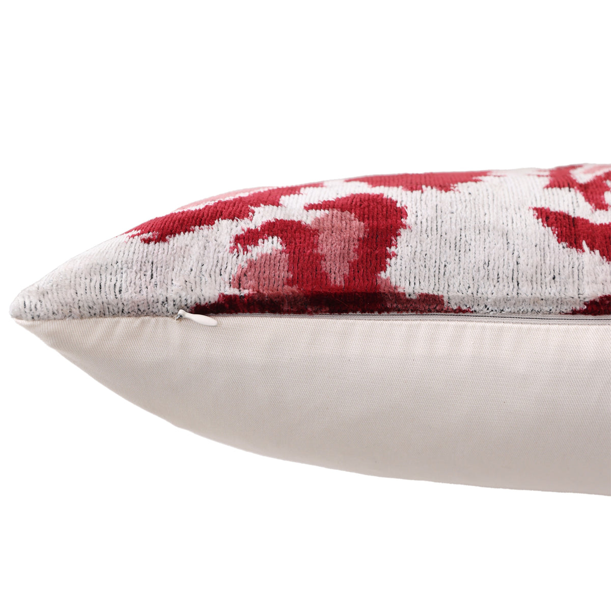 Hidden zipper closure along the edge of a crimson and silvery off-white velvet pillow