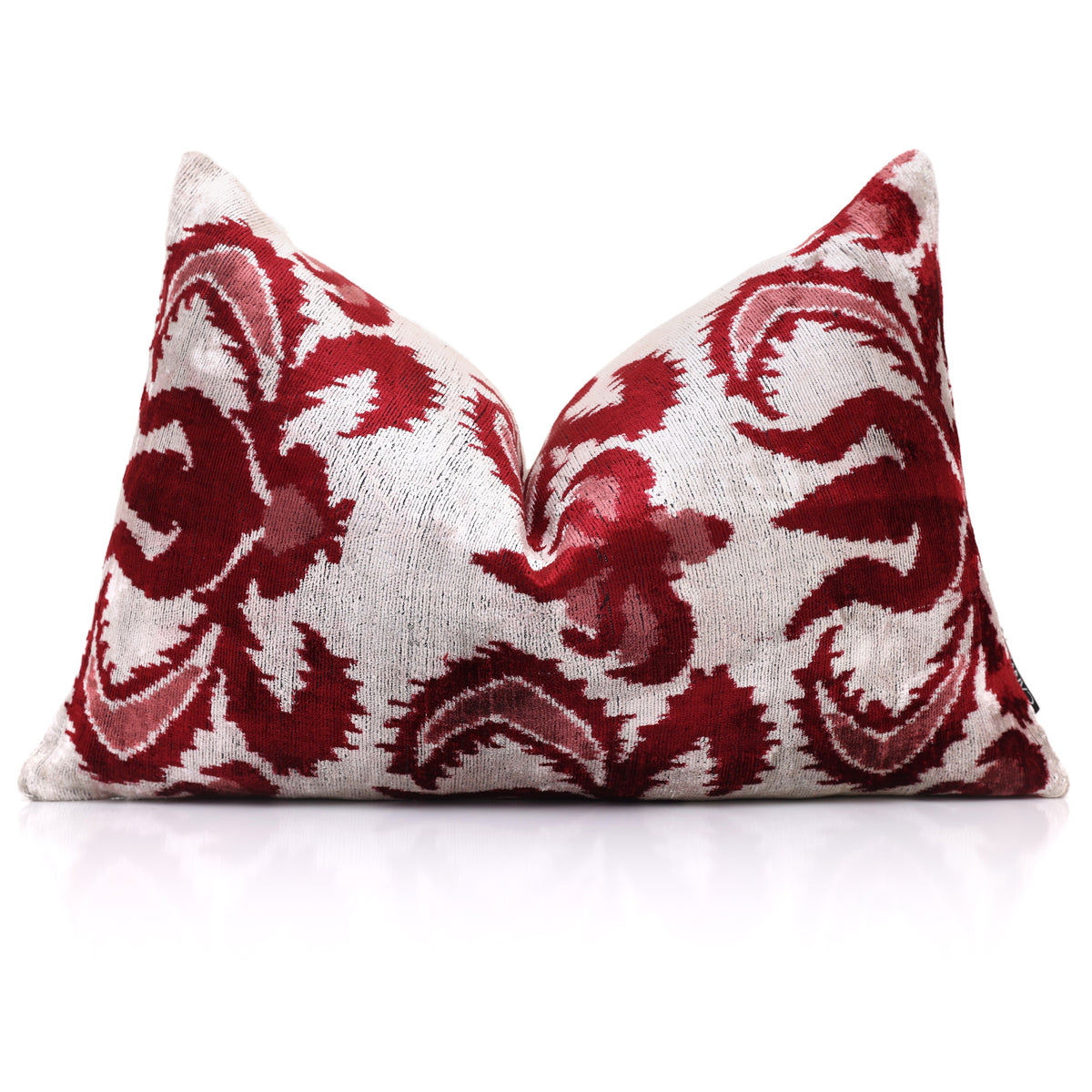 Styled silvery off-white lumbar pillow with crimson ikat medallion standing upright