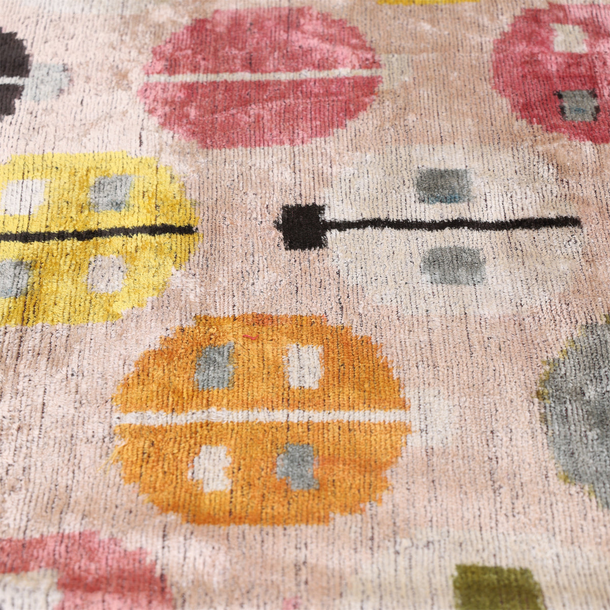 Angled detail of geometric circular medallions in pale blush beige, gold, black and olive green velvet