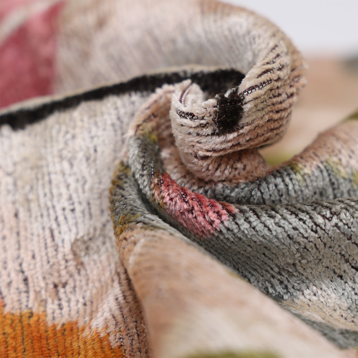 Folded silk velvet showing the textured pile in pale blush beige and multicolor geometric pattern