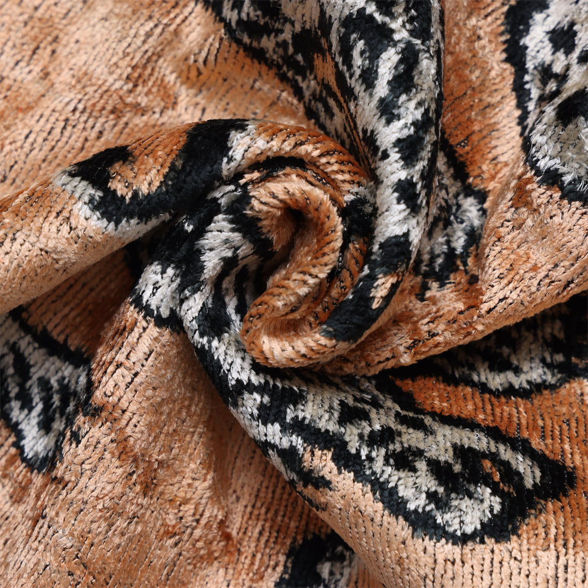 Close-up of warm camel tan silk velvet showing plush pile and black tiger pattern