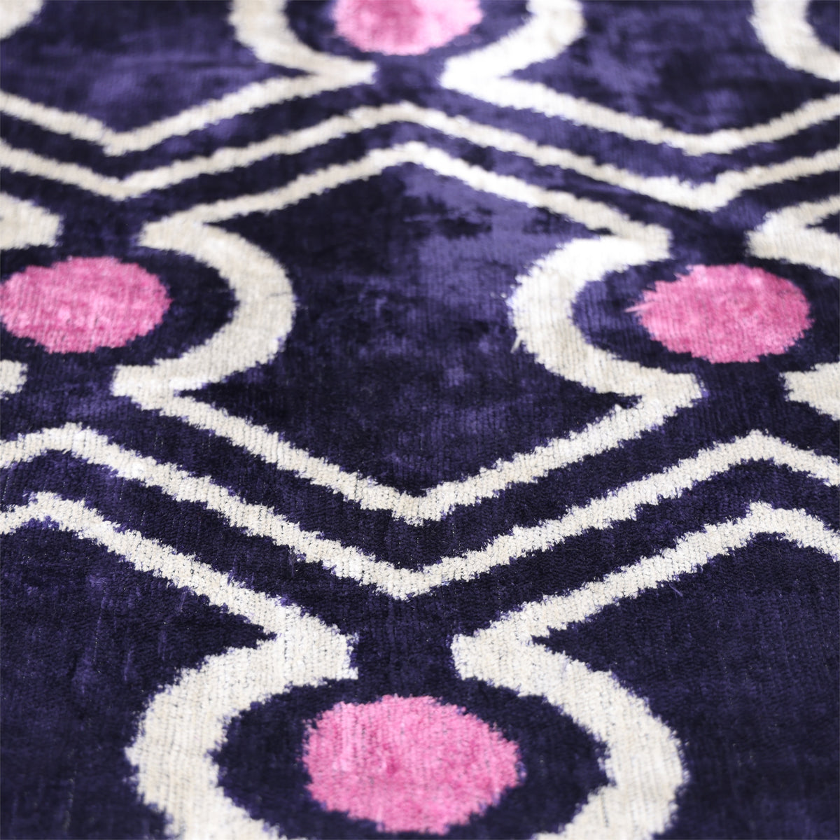 Angled detail of deep indigo purple, white and mauve pink geometric ikat velvet