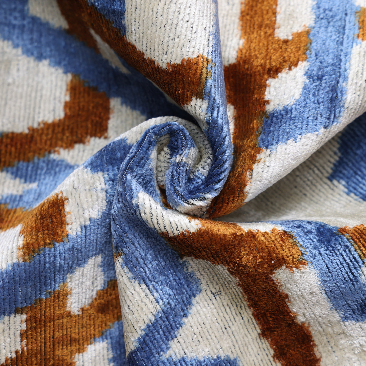 Swirled pale ivory, cornflower blue and cognac rust velvet showing the ribbed pile