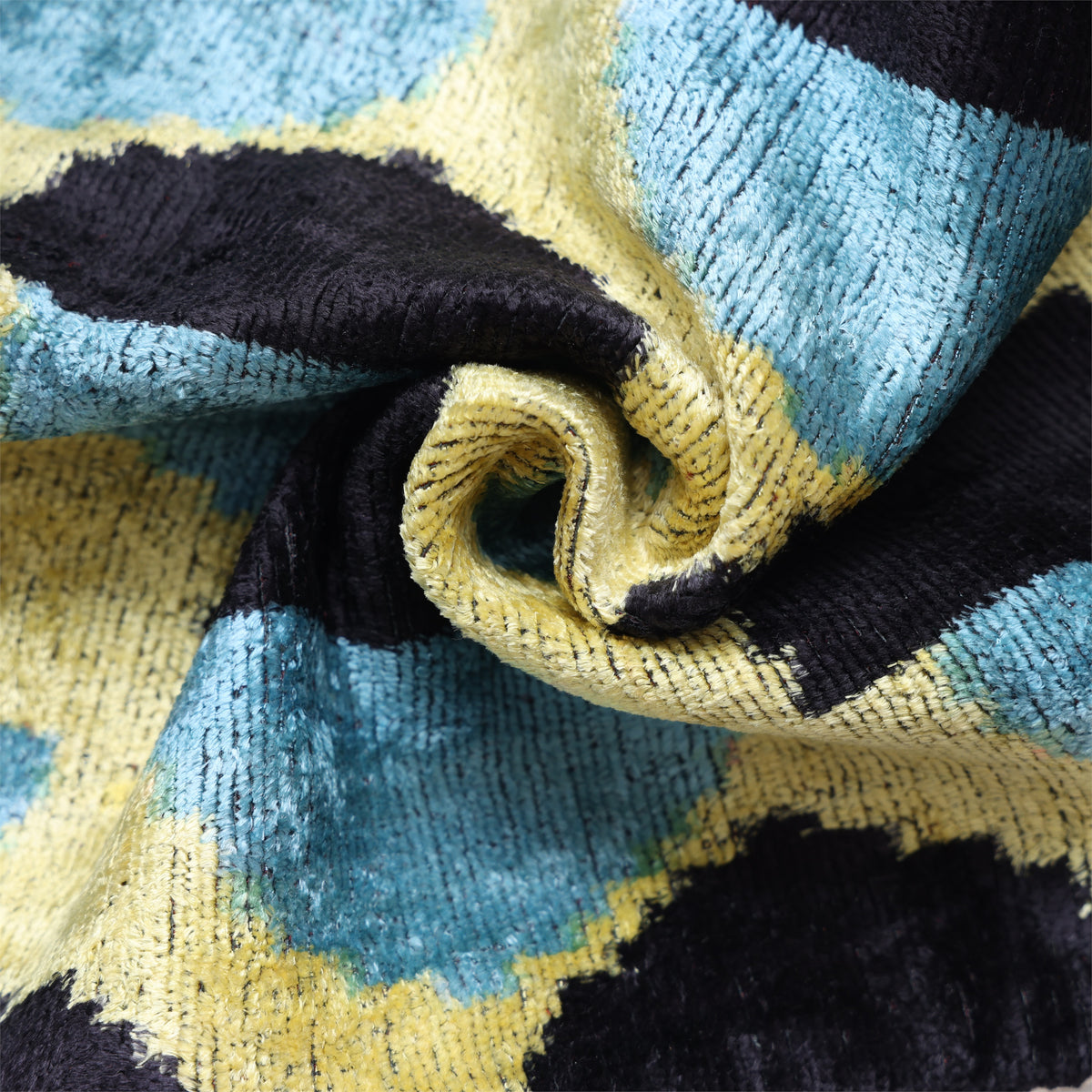 Folded black, slate blue and chartreuse yellow silk velvet showing soft pile and ikat pattern