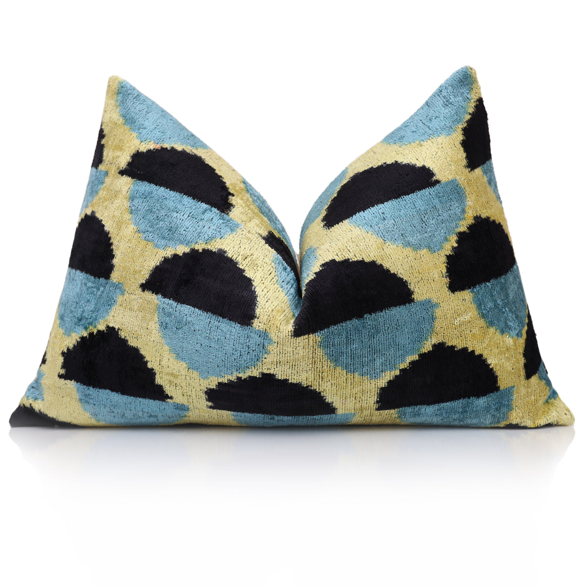 Styled black, slate blue and chartreuse yellow ikat lumbar pillow with a shaped center on reflective white surface