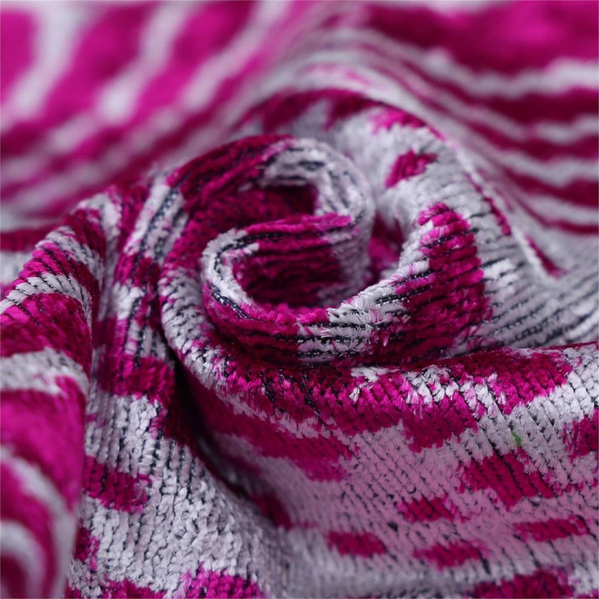 Close-up of magenta pink and crisp white velvet showing folded plush texture and weave