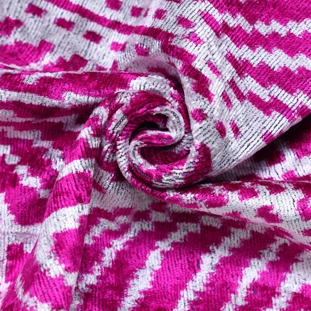 Overhead close-up of swirled magenta pink and crisp white velvet fabric