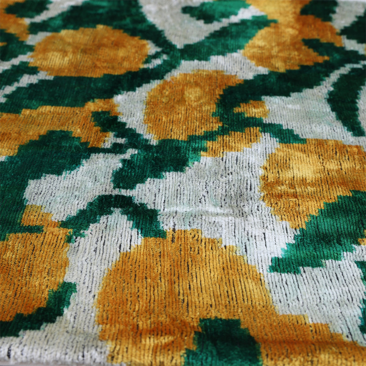 Angled surface detail of emerald green and ochre gold ribbed silk velvet