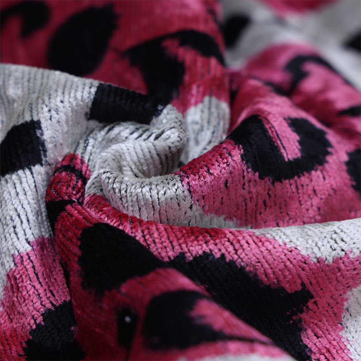 Macro view of crumpled silk velvet with magenta pink, black and silvery white sheen
