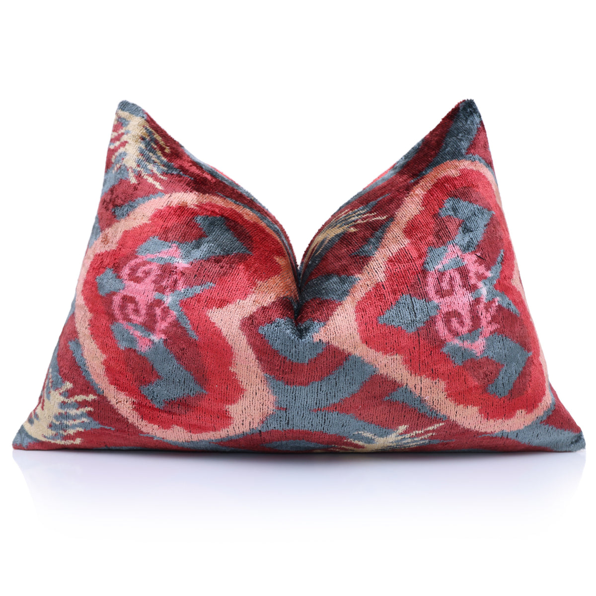 Front view of the crimson red and slate blue-gray ikat lumbar pillow styled with a center crease