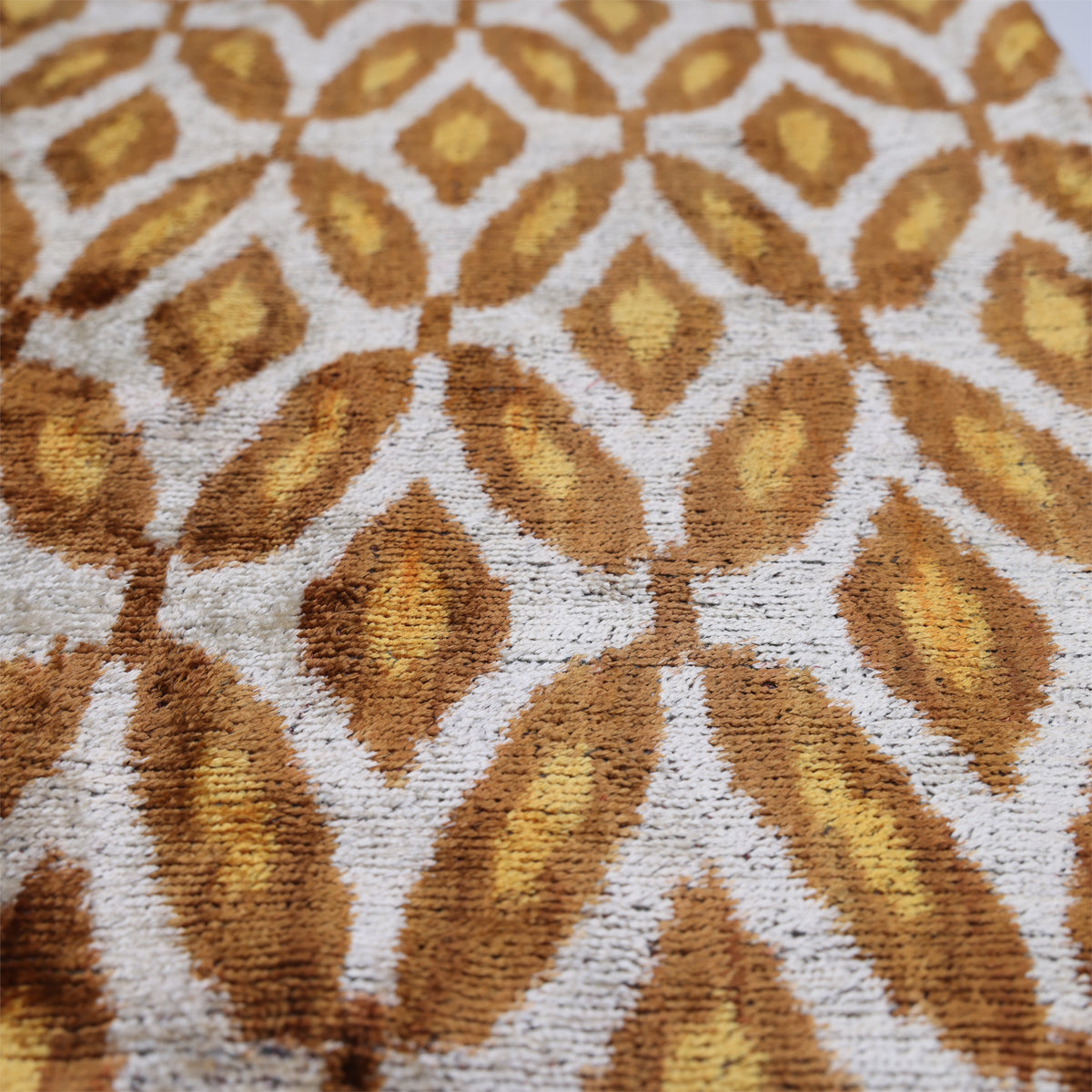 Angled detail of caramel brown and mustard gold geometric pattern on velvet