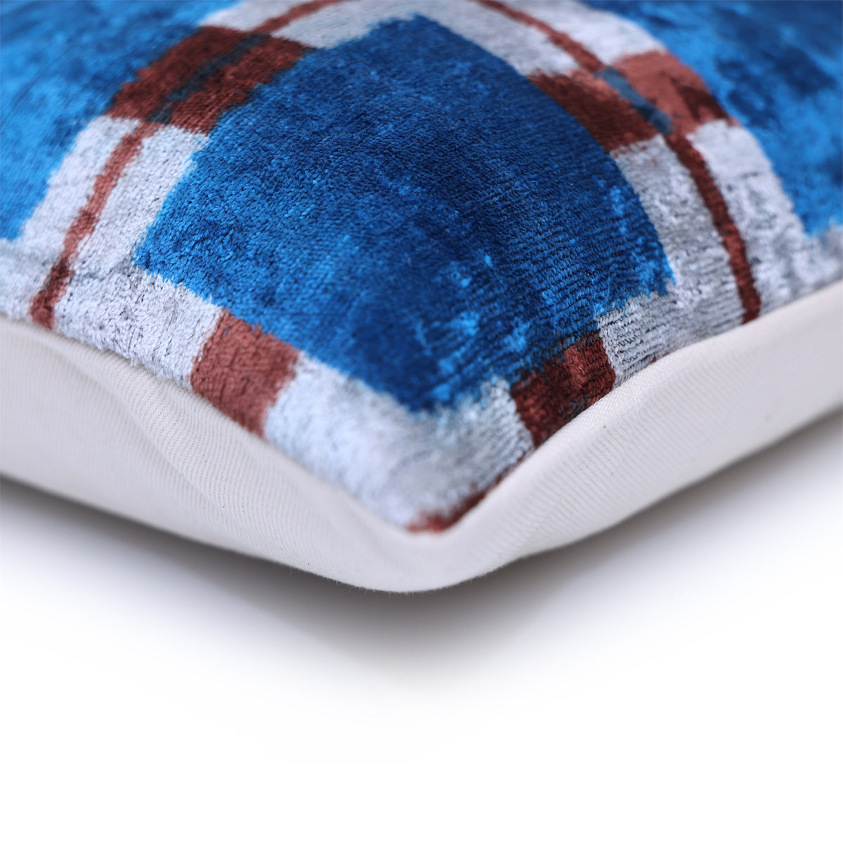 Corner seam and woven backing of a cobalt blue, silvery white and reddish brown plaid pillow