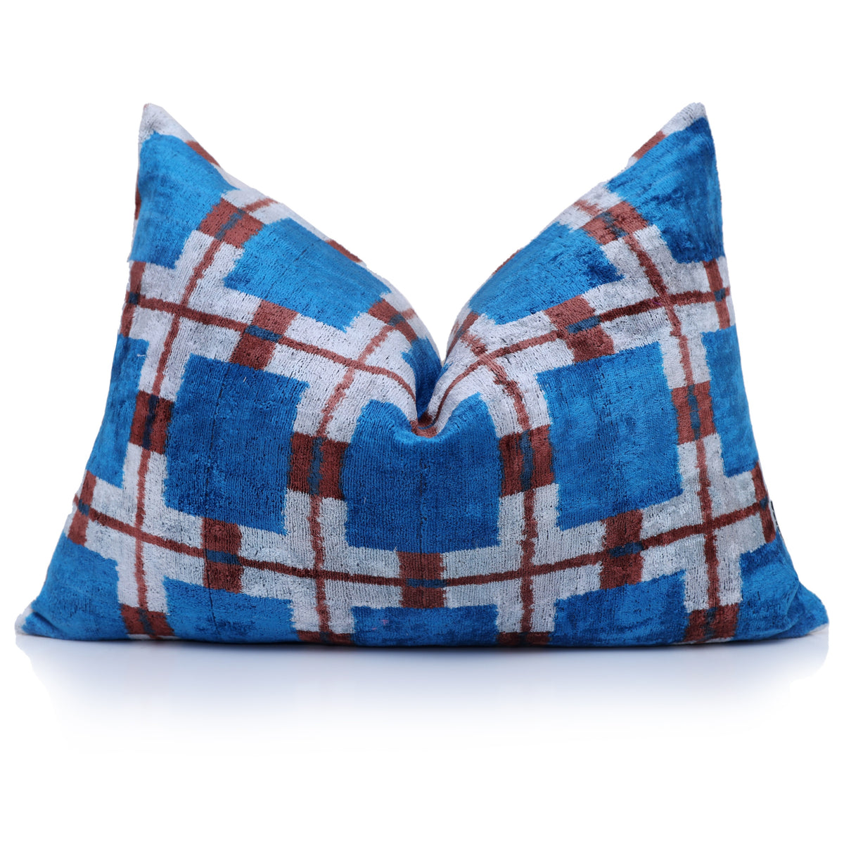 Upright cobalt blue plaid lumbar pillow with a center karate chop on reflective white surface