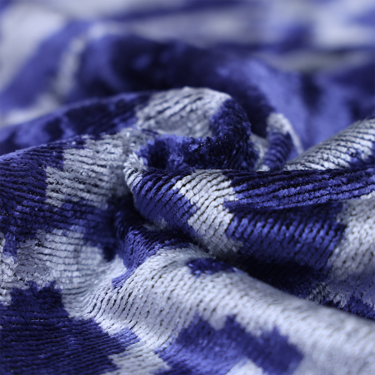 Fabric folds reveal cobalt blue velvet weave and luminous silvery light gray sheen